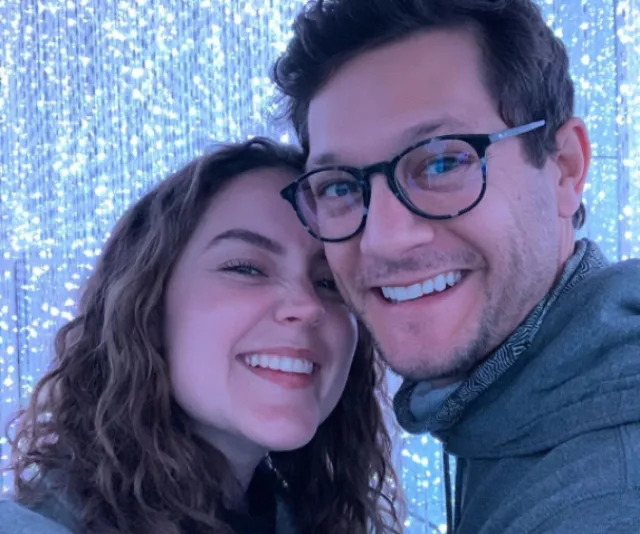 Couple smiling in front of sparkling light backdrop.