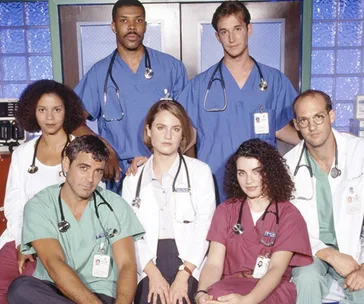 Cast of "ER" in scrubs and lab coats, posing in a hospital setting.