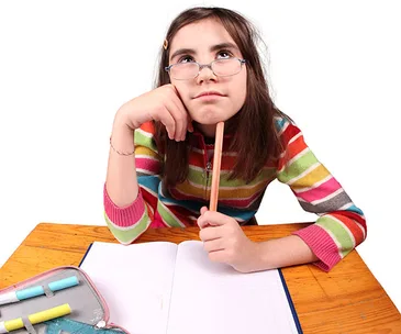 Girl in colorful sweater, glasses, thinking with pencil at a desk, open notebook in front.
