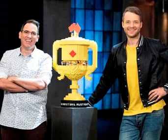 Two men stand beside a large Lego trophy on "Lego Masters Australia".