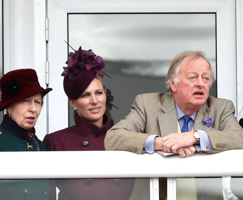Group of three people standing together outdoors, dressed formally, with a man in front.