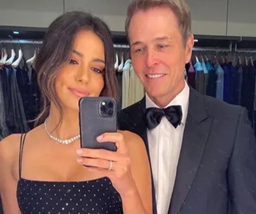 Couple dressed elegantly taking a mirror selfie.