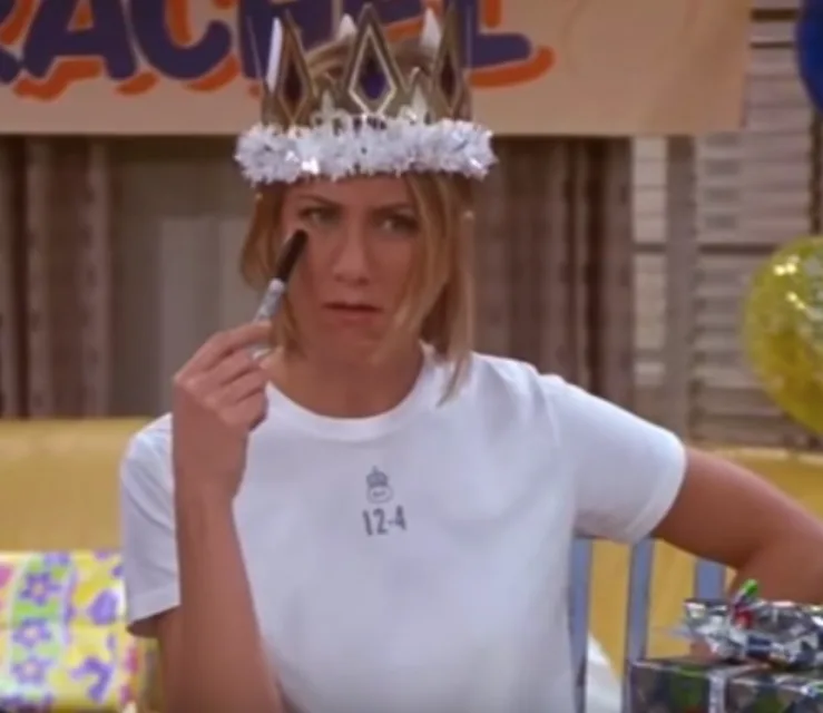 Woman wearing a crown holding a marker, looks puzzled during a festive gathering.