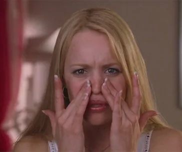 A person pinching their nose with both hands, appearing to examine their skin closely.