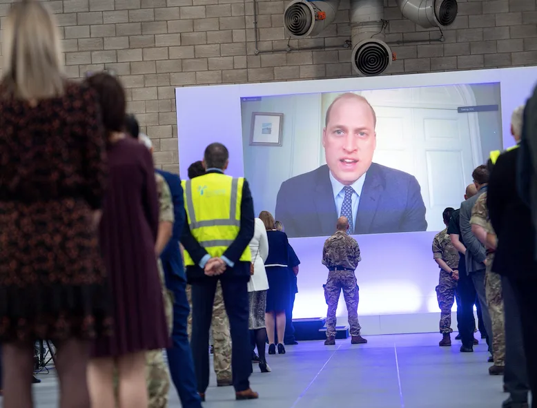 People watch a virtual speech on a screen at an NHS hospital opening ceremony.
