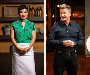 A woman in a green top and apron next to a man in a black shirt on a cooking show set with warm lighting.