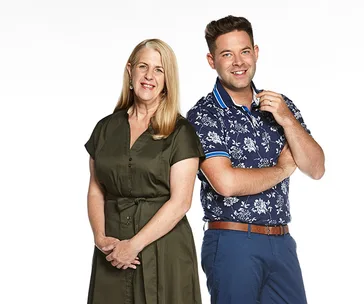 Two people smiling, one wearing a green dress, the other in a floral shirt, against a white background.