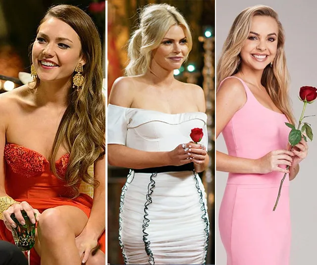 Three women from 'The Bachelorette Australia' in elegant dresses, each holding a red rose, smiling at the camera.