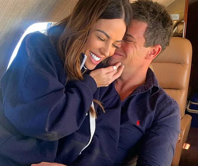 Couple smiling and embracing while seated in an airplane.