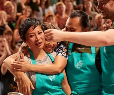 Poh and fellow contestants embrace emotionally during a MasterChef Australia moment, with onlookers in the background.
