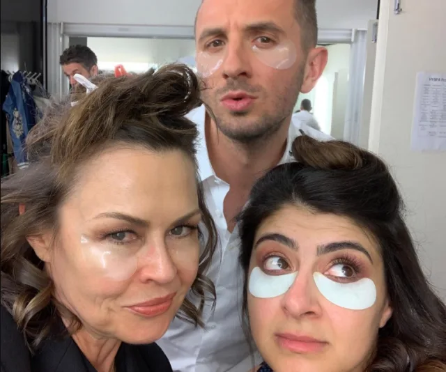 Three people with eye patches posing in a bathroom, smiling and looking at the camera.