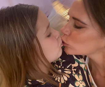 A person kisses a small child on the lips, showing affection in a sweet close-up capture.