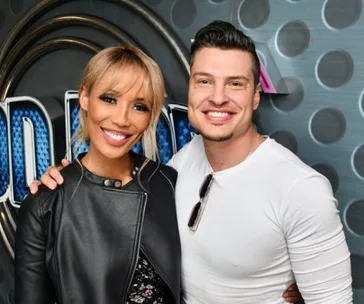 Individuals smiling at a public event, posing together in front of a decorative background.