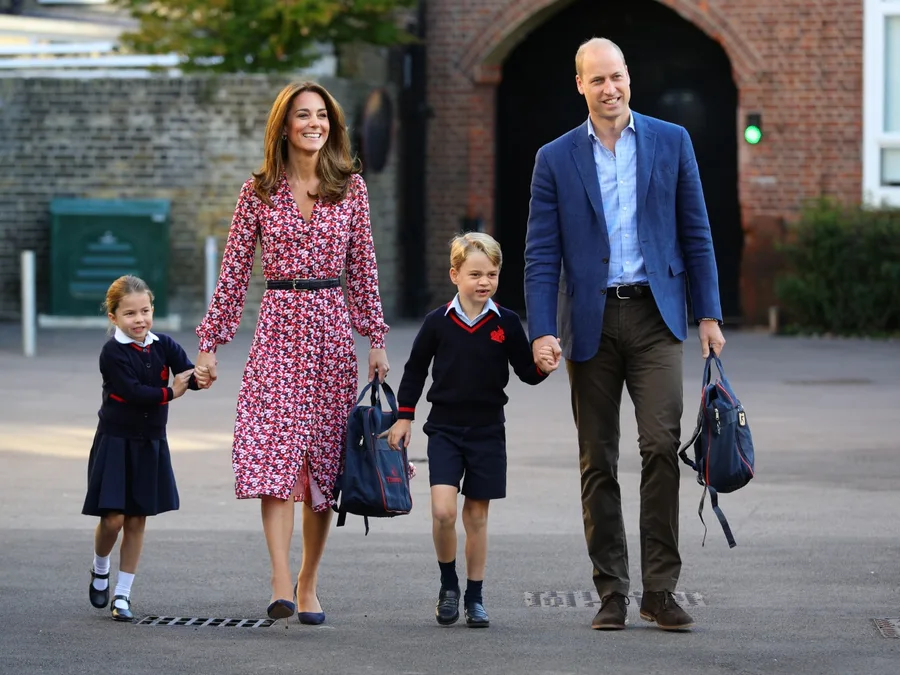 A family with two children in school uniforms walking happily together, carrying backpacks.