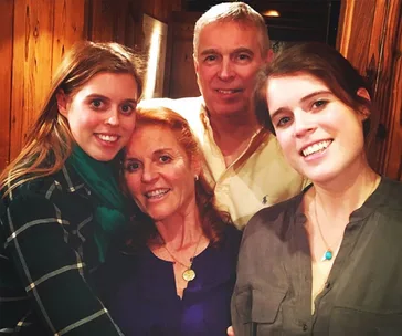 A family taking a cozy group photo indoors, smiling warmly at the camera.