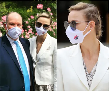 Two people wearing white face masks and sunglasses outdoors, next to pink flowers.