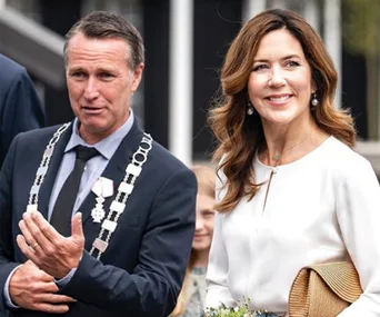 Two individuals in formal attire, one woman smiling, outdoors at an event.