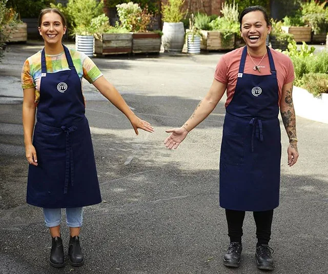 Contestants wearing aprons smile in an outdoor setting with greenery in the background.
