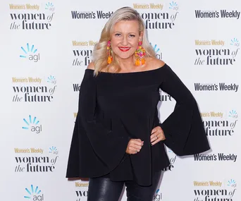 Person in a black off-shoulder top, posing at Women's Weekly "Women of the Future" event backdrop.
