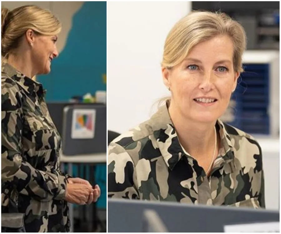 A woman in a camouflage dress smiling and engaged in conversation, with office background.