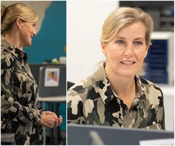 A woman in a camouflage dress smiling and engaged in conversation, with office background.