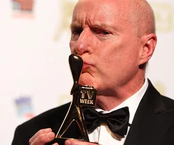 Man in tuxedo kissing a Logie award; actor from "Home and Away."