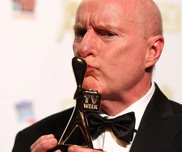 Man in tuxedo kissing a Logie award; actor from "Home and Away."