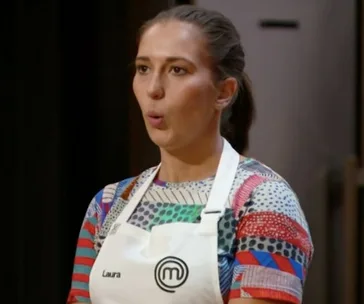 Contestant on MasterChef wearing a colorful shirt and apron, looking surprised.