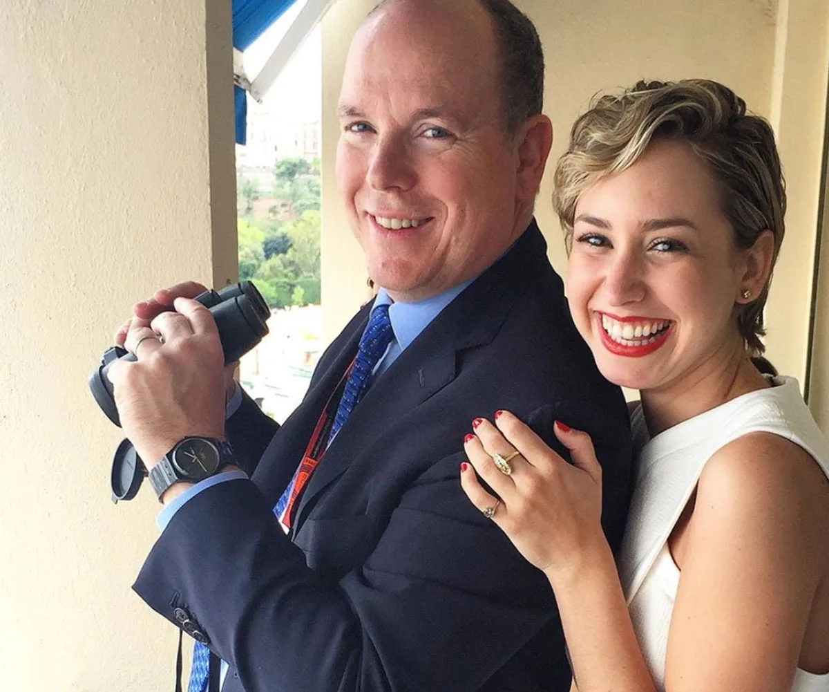 Father and daughter smiling together, the man holds binoculars and wears a suit, while the woman wears a white dress.