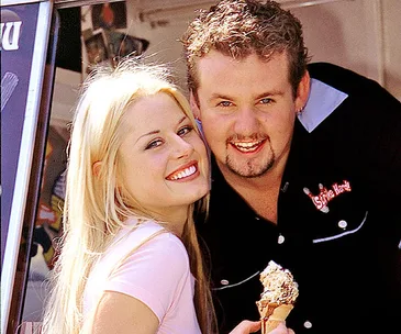 A smiling couple enjoying an ice cream together outside an ice cream truck.