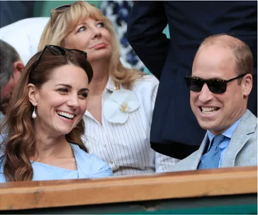 A couple laughing and smiling while sitting in the audience at a sports event.