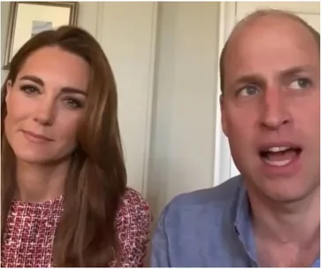 Two people sitting indoors, one with long hair and another speaking, wearing a red-patterned outfit and blue shirt.
