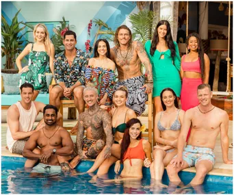 Group of contestants from "Bachelor in Paradise" posing by a pool, tropical setting, everyone smiling.
