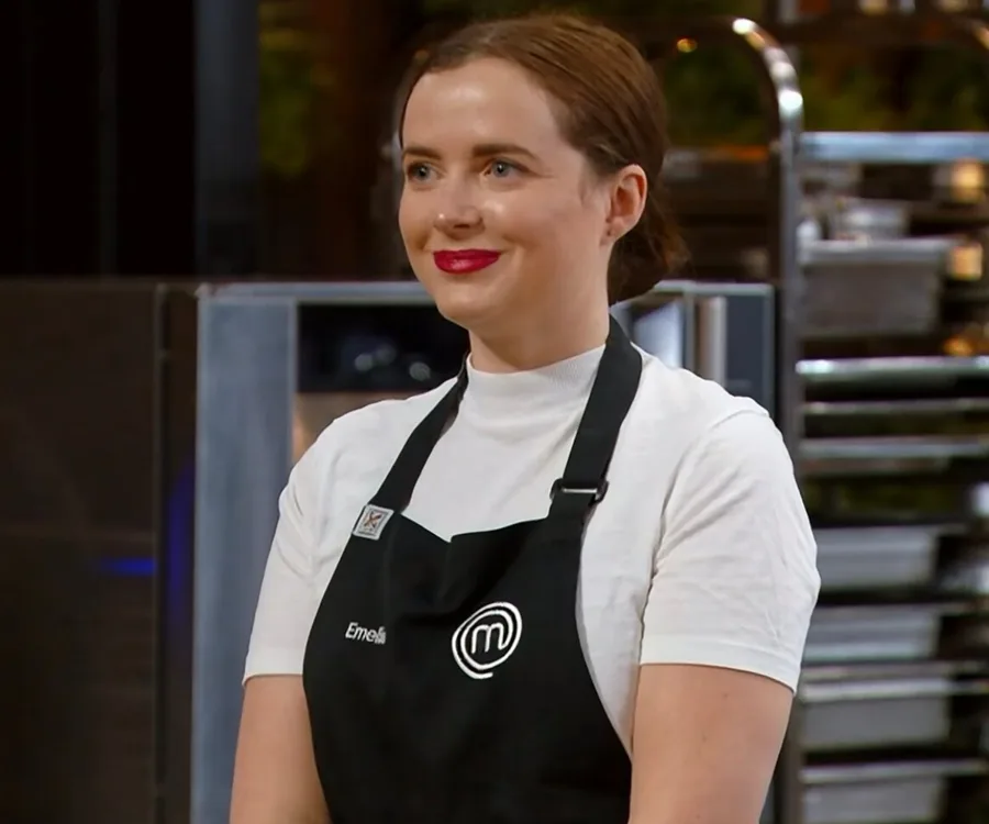 Emelia Jackson wearing a black MasterChef apron, smiling in a kitchen setting.