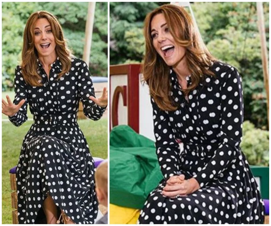 Woman in a black polka dot dress, smiling and animated, outdoors with greenery in the background.