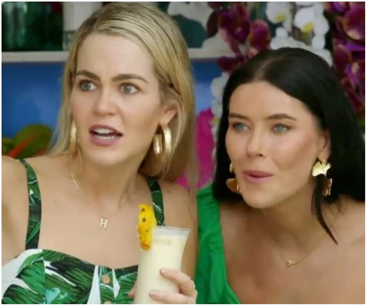 Two women from Bachelor in Paradise Australia 2021 looking surprised, one holding a tropical drink.