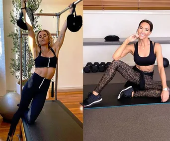 Women in activewear exercising indoors; one on a reformer, the other seated on a yoga mat with dumbbells nearby.