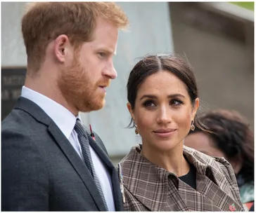 A couple in formal attire, standing side by side, with the woman looking at the man attentively.