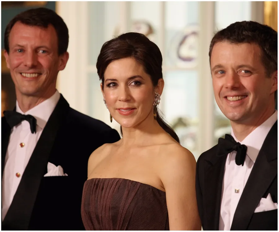 Three people in formal attire, smiling at an event.