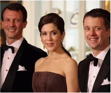 Three people in formal attire, smiling at an event.