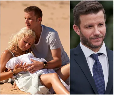 A man and woman on a beach with a baby; a man in a suit is on the right.