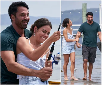 Two people happily fishing and walking on a beach pier.
