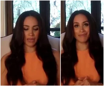 Meghan Markle in an orange top, speaking in a video call with a window and trees in the background.