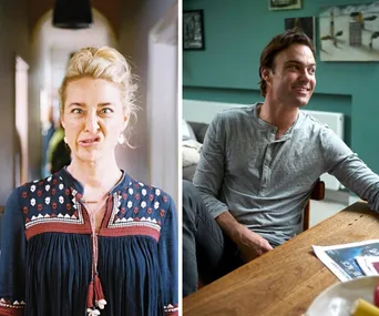 A woman making a funny face and a man smiling, seated indoors beside a table with a newspaper.
