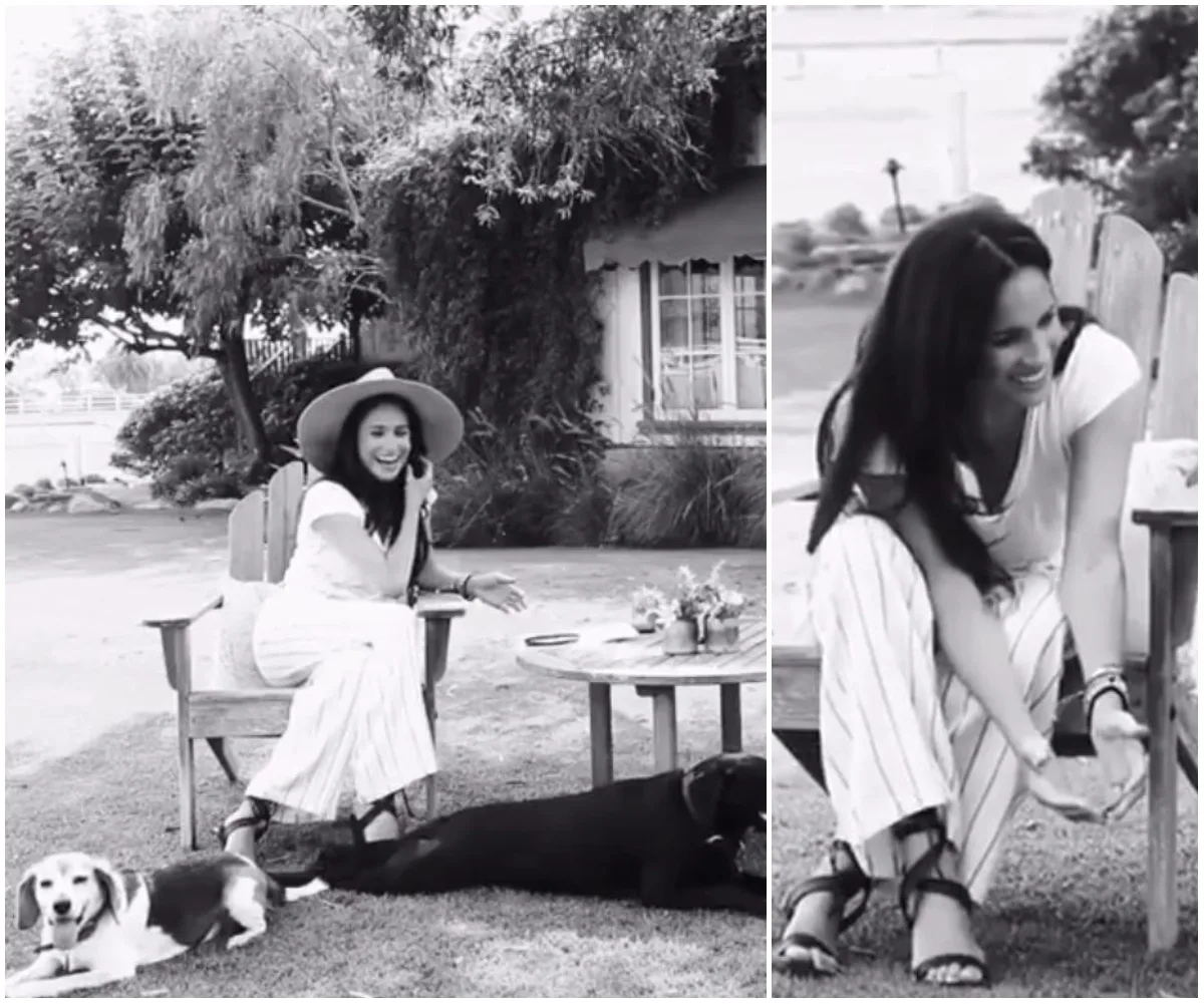 Meghan Markle sitting outdoors with two dogs, smiling and wearing a hat, surrounded by trees and flowers.