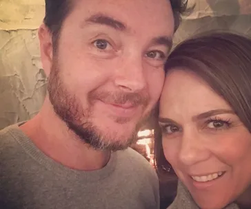 A couple close together, both smiling warmly at the camera.