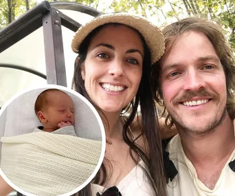 Family selfie outdoors with a smiling man and woman; inset of a sleeping baby wrapped in a cream blanket.