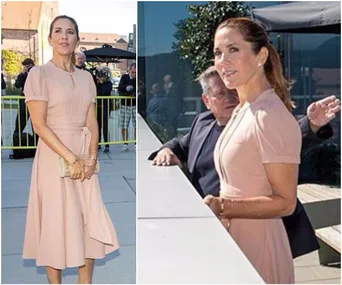Princess Mary in a light pink dress, standing outdoors, holding a clutch amidst a crowd.