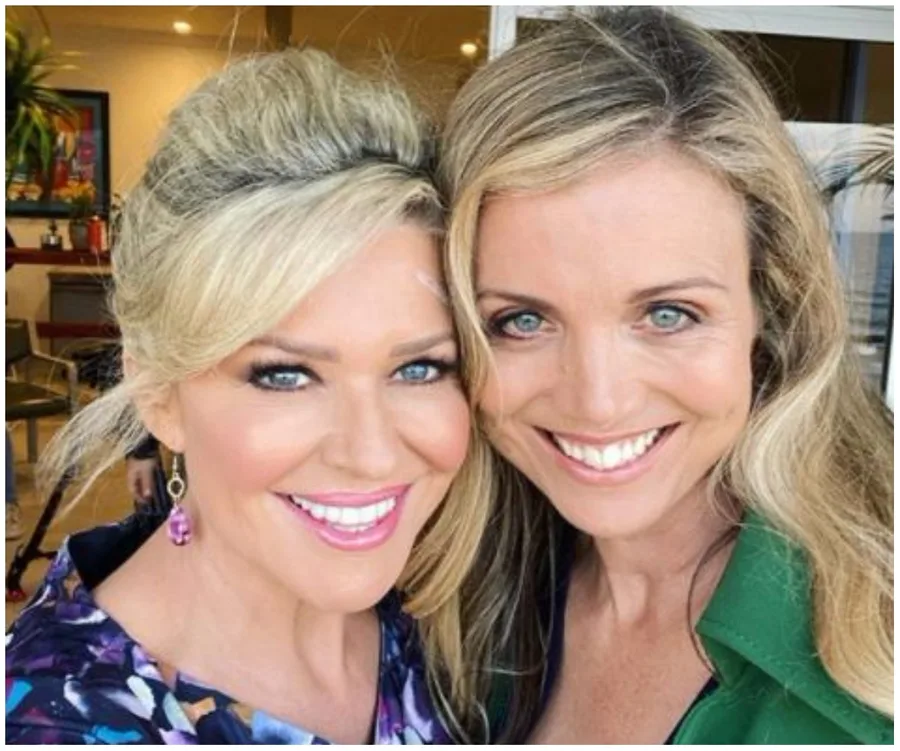 Two smiling women take a selfie together indoors with a warm ambiance.