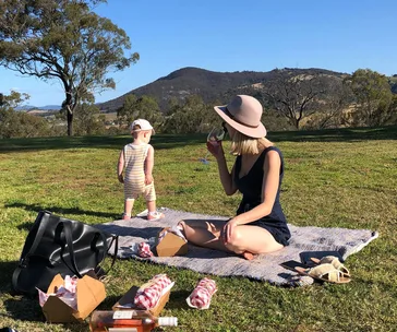Woman and child enjoying a picnic on a sunny day in Hunter Valley, Australia with scenic mountain views.